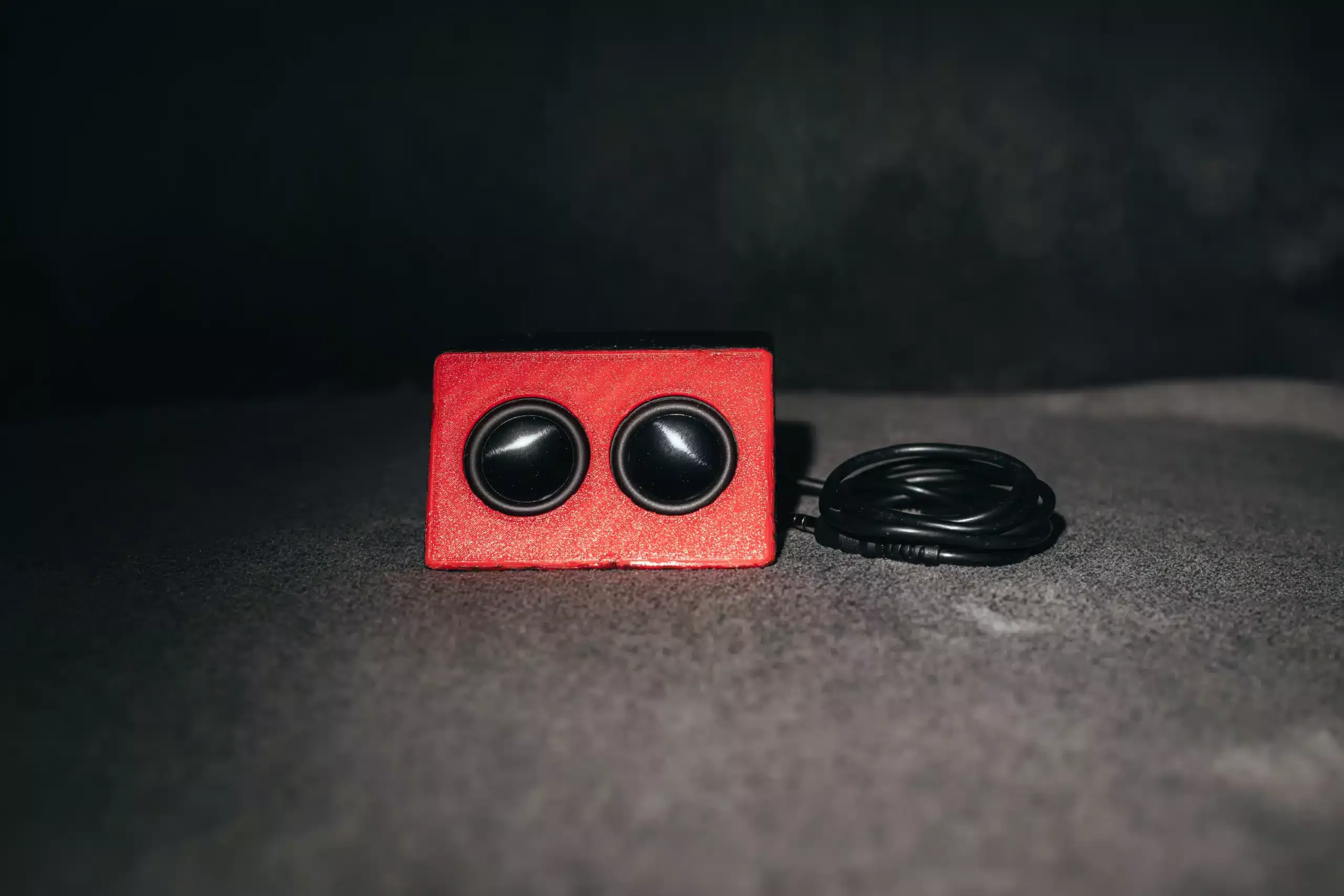 Front-view of a small home-made speaker with an audio cable connected to it